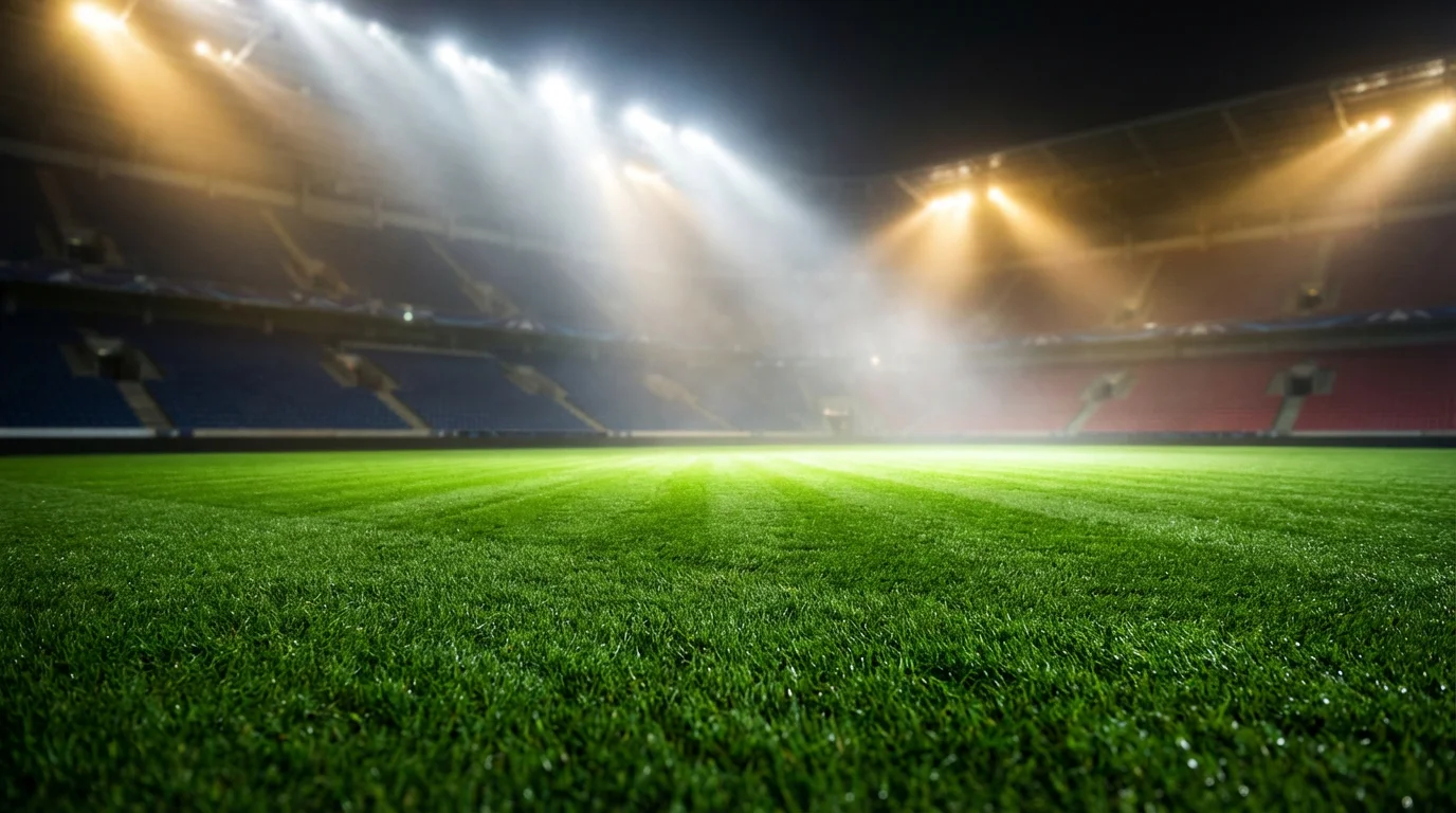 Estadio de fútbol iluminado con césped verde antes de un partido nocturno
