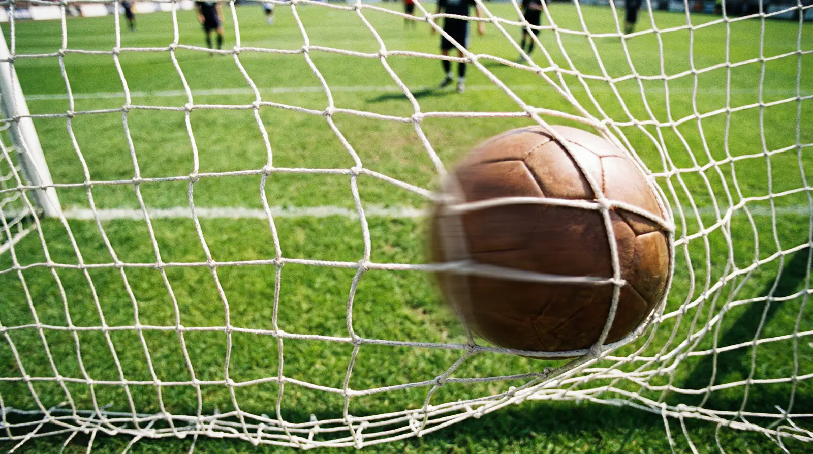Red de portería de fútbol vista desde dentro con un balón entrando tras un disparo